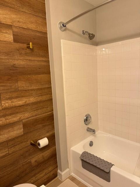 bathroom featuring  shower combination, toilet, and wooden walls