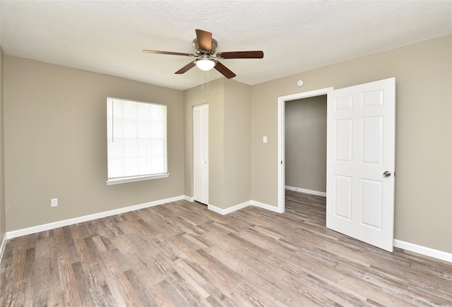 unfurnished bedroom with ceiling fan, light wood-type flooring, a closet, and a textured ceiling