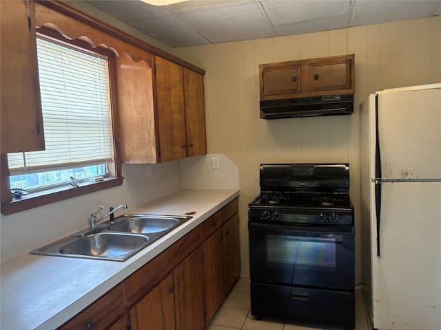 kitchen featuring light tile patterned floors, sink, white fridge, and black range with gas cooktop