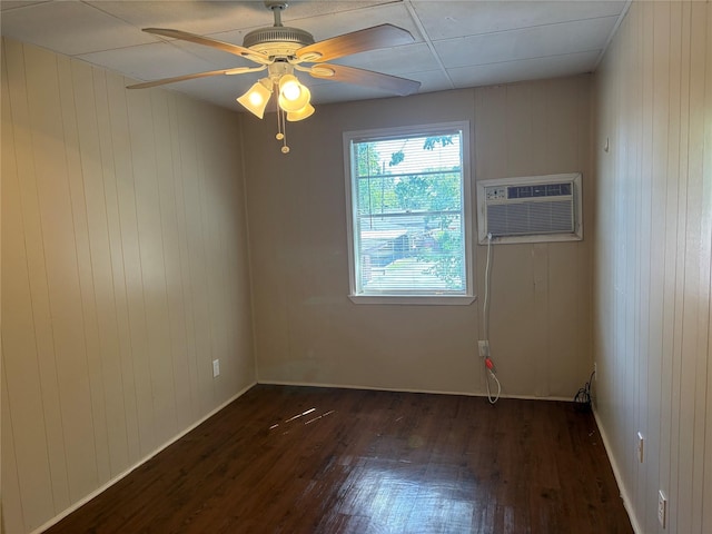 unfurnished room featuring a wall mounted AC, ceiling fan, dark hardwood / wood-style flooring, and wooden walls