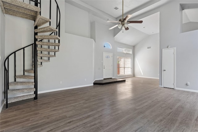 unfurnished living room featuring a towering ceiling, ceiling fan, and dark wood-type flooring