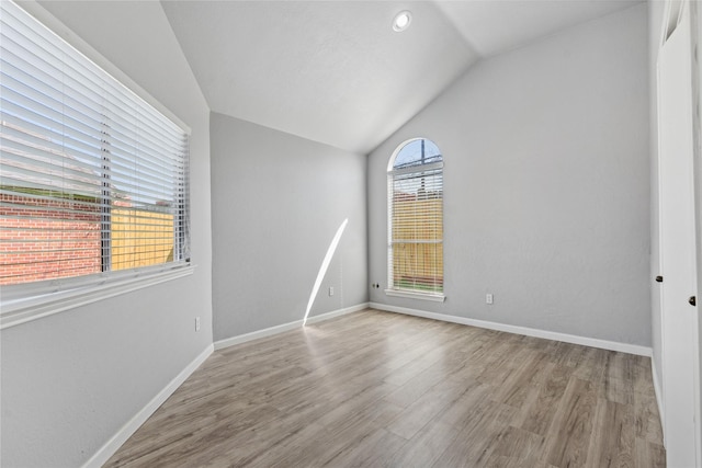 empty room with light hardwood / wood-style flooring and vaulted ceiling