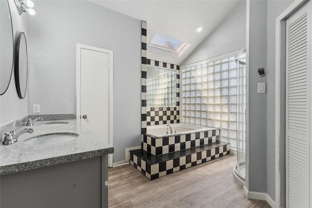 bathroom with hardwood / wood-style flooring, vanity, a healthy amount of sunlight, and lofted ceiling with skylight