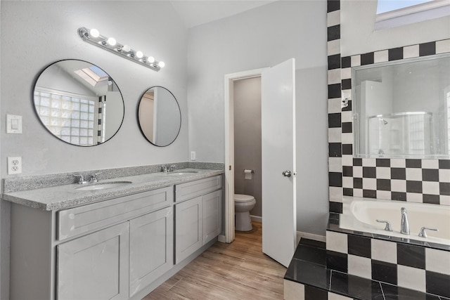 full bathroom with hardwood / wood-style floors, vanity, independent shower and bath, and toilet