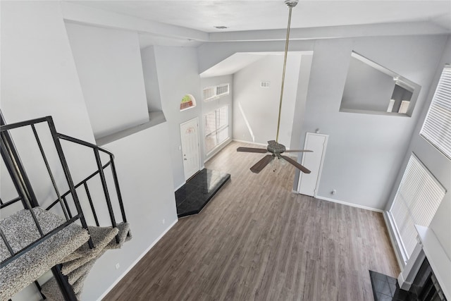 interior space featuring ceiling fan, wood-type flooring, and a high ceiling