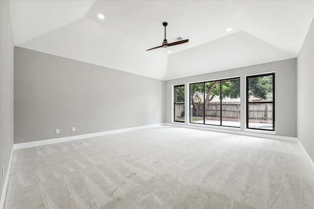 interior space with a raised ceiling, ceiling fan, light colored carpet, and lofted ceiling