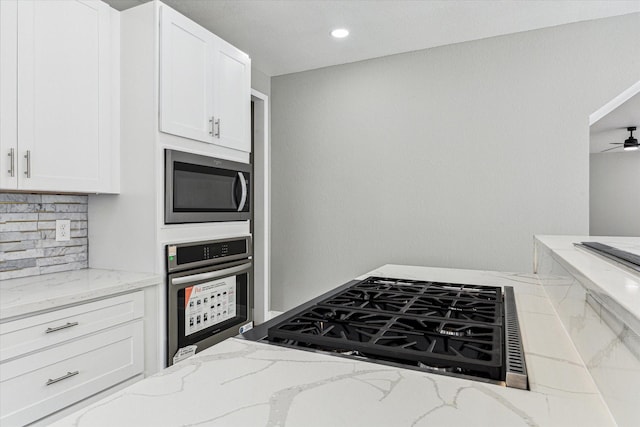 kitchen with light stone counters, white cabinetry, and stainless steel appliances