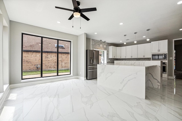 kitchen with white cabinetry, hanging light fixtures, light stone counters, a kitchen island, and appliances with stainless steel finishes