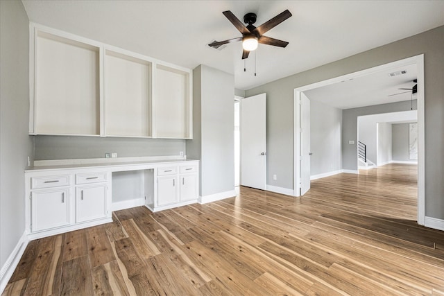 interior space featuring built in desk, light hardwood / wood-style floors, and ceiling fan