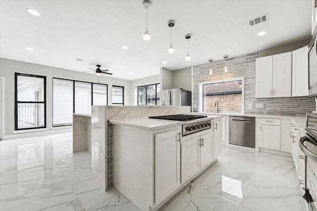 kitchen featuring white cabinets, ceiling fan, stainless steel appliances, and hanging light fixtures