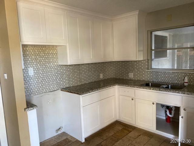 kitchen with backsplash, white cabinetry, and dark stone counters