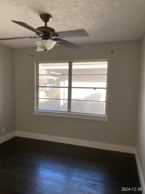 empty room with ceiling fan, wood-type flooring, and a textured ceiling