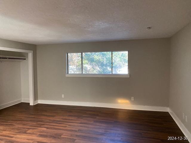 unfurnished bedroom with a closet, dark hardwood / wood-style flooring, and a textured ceiling