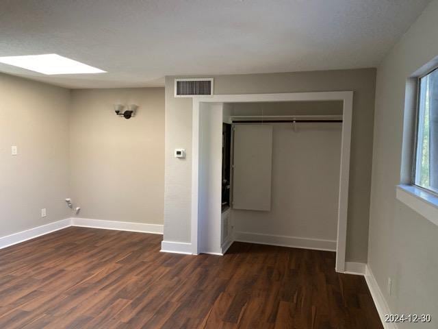 unfurnished bedroom featuring dark hardwood / wood-style floors, a skylight, and a closet