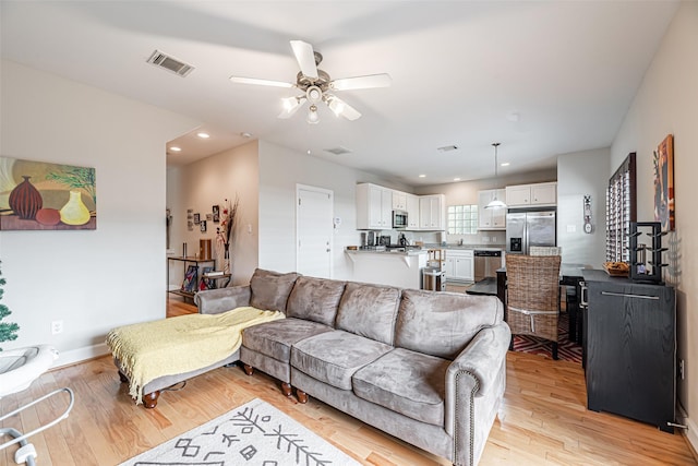 living room with ceiling fan and light hardwood / wood-style flooring