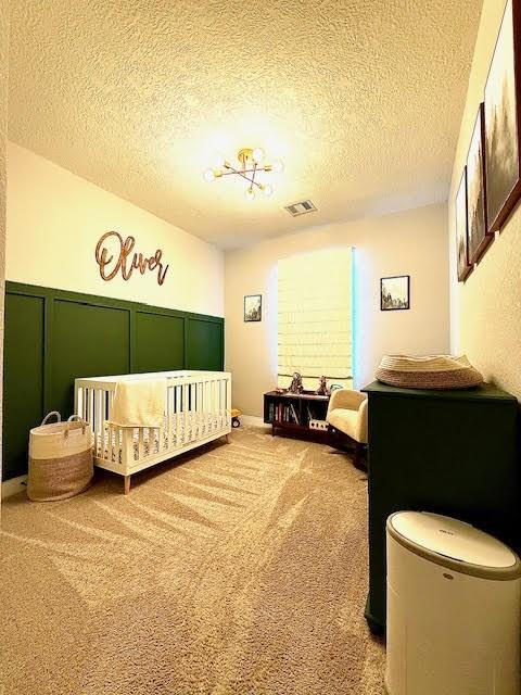 bedroom featuring carpet, a textured ceiling, and a nursery area