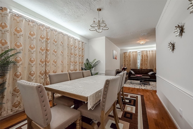 dining space featuring dark hardwood / wood-style floors, an inviting chandelier, and a textured ceiling