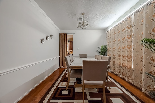 dining space featuring a textured ceiling, a chandelier, crown molding, and dark hardwood / wood-style floors