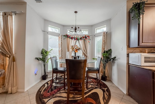 tiled dining area featuring a chandelier and ornamental molding