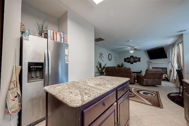 kitchen with dark brown cabinetry, a center island, stainless steel fridge with ice dispenser, ceiling fan, and light tile patterned floors