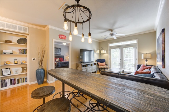 dining space with built in shelves, crown molding, ceiling fan, and light wood-type flooring