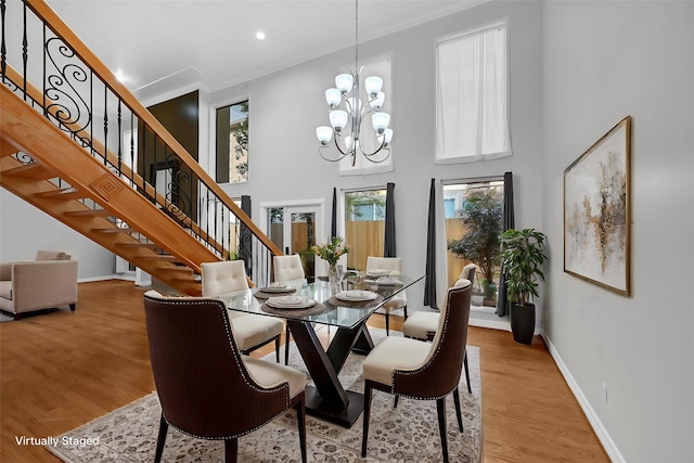 dining room featuring a chandelier, a high ceiling, light wood-type flooring, and ornamental molding