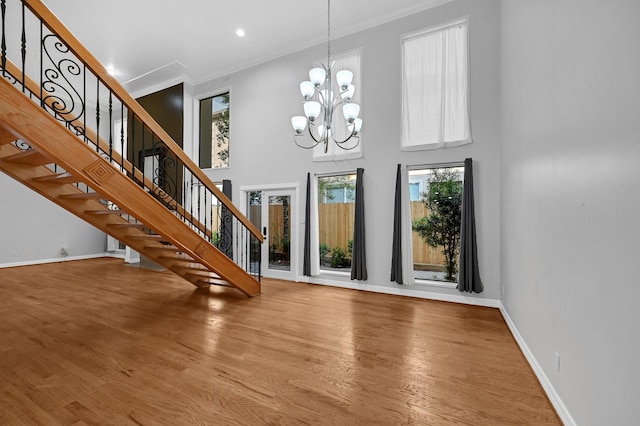 foyer entrance featuring hardwood / wood-style flooring, a towering ceiling, a wealth of natural light, and a chandelier