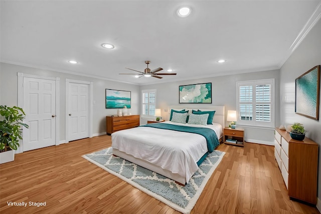 bedroom with ceiling fan, light hardwood / wood-style floors, crown molding, and multiple closets