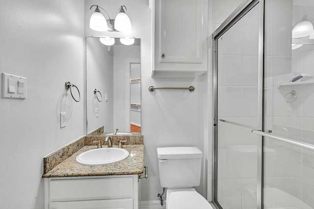 bathroom with vanity, toilet, and a shower with door