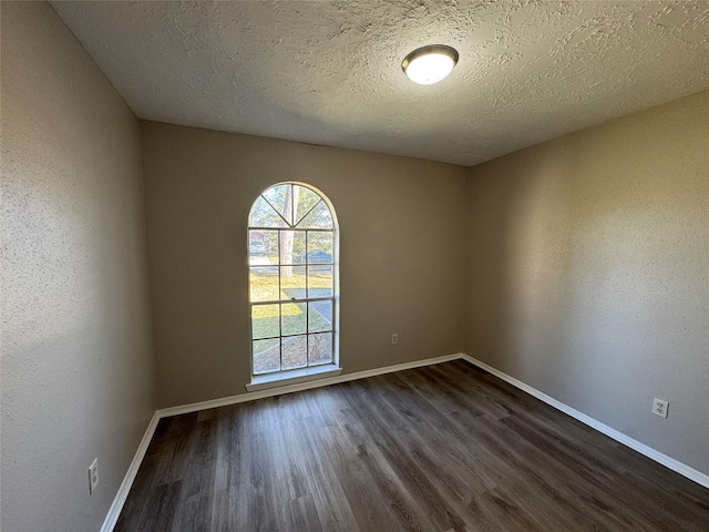 spare room with a textured ceiling and dark wood-type flooring