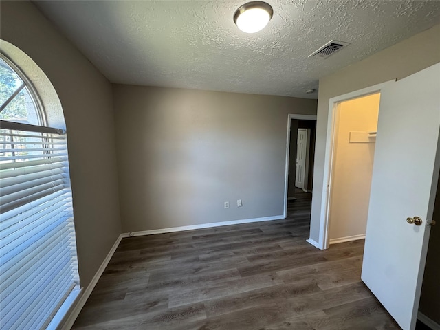 empty room featuring a textured ceiling and dark wood-type flooring