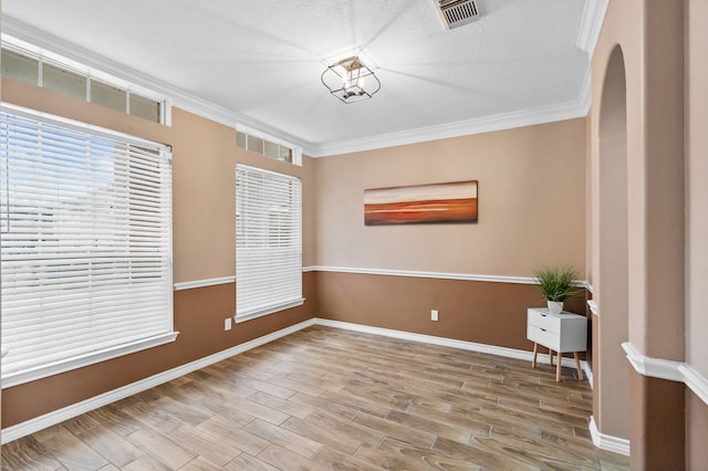 spare room with a textured ceiling, light hardwood / wood-style flooring, and crown molding