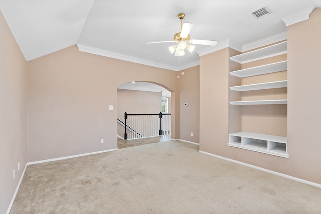 unfurnished room with ceiling fan, carpet floors, crown molding, and built in shelves