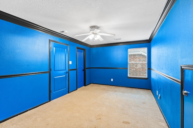 carpeted empty room featuring a textured ceiling, ceiling fan, and crown molding