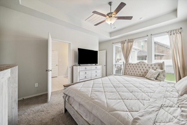 carpeted bedroom with a tray ceiling and ceiling fan