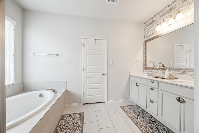 bathroom featuring tiled bath, a wealth of natural light, tile patterned flooring, and vanity