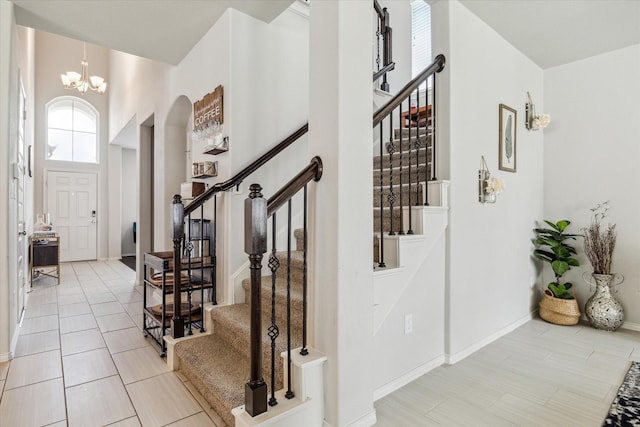 tiled foyer entrance featuring a notable chandelier and a towering ceiling