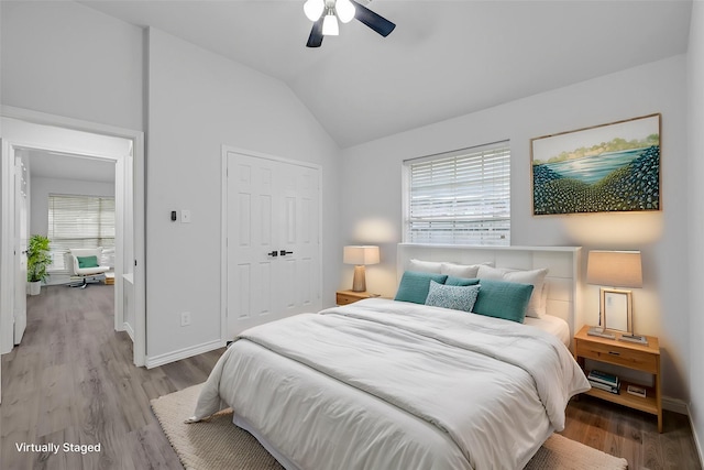 bedroom with ceiling fan, lofted ceiling, light wood-type flooring, and a closet