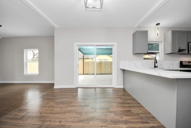 kitchen with dark hardwood / wood-style flooring, beam ceiling, gray cabinets, and light stone countertops