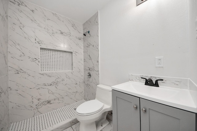 bathroom featuring a tile shower, vanity, and toilet