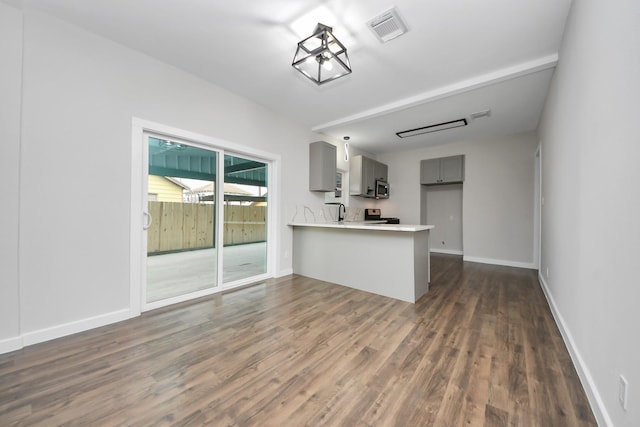 kitchen featuring sink, dark hardwood / wood-style flooring, gray cabinets, kitchen peninsula, and stove