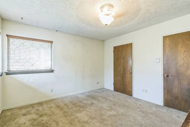 unfurnished room featuring light colored carpet and a textured ceiling