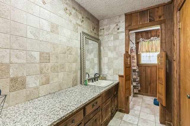 bathroom featuring tile patterned floors, vanity, a textured ceiling, and tile walls