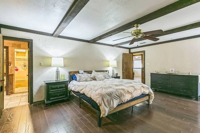 bedroom featuring dark wood-type flooring, ensuite bathroom, ceiling fan, a textured ceiling, and beamed ceiling