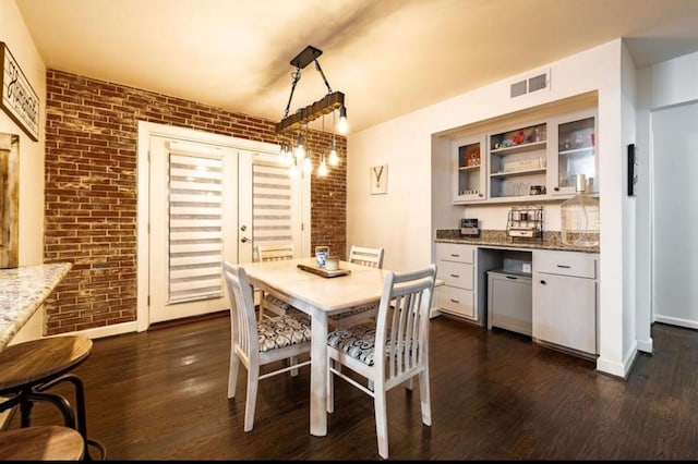 dining room with dark wood-type flooring and brick wall