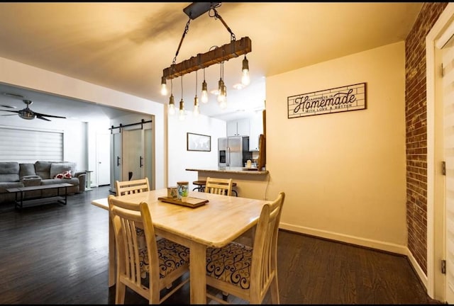 dining area featuring ceiling fan, dark hardwood / wood-style floors, a barn door, and brick wall