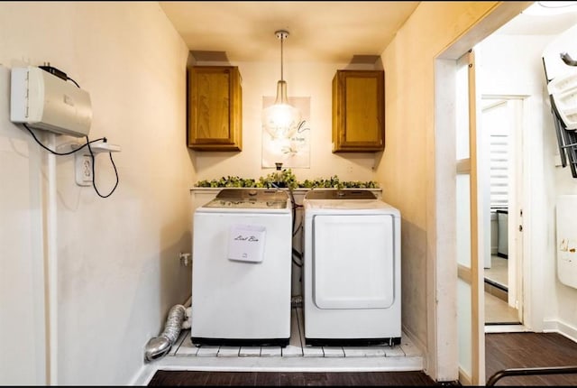 laundry area with cabinets, washing machine and dryer, and hardwood / wood-style flooring