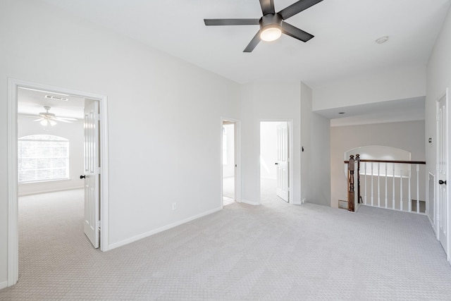 carpeted empty room with a towering ceiling and ceiling fan