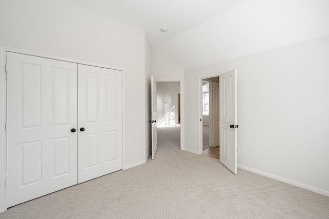 unfurnished bedroom with a closet, vaulted ceiling, and light carpet