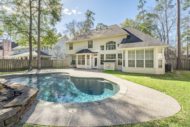 back of house with a lawn, central air condition unit, a fenced in pool, a sunroom, and a patio area